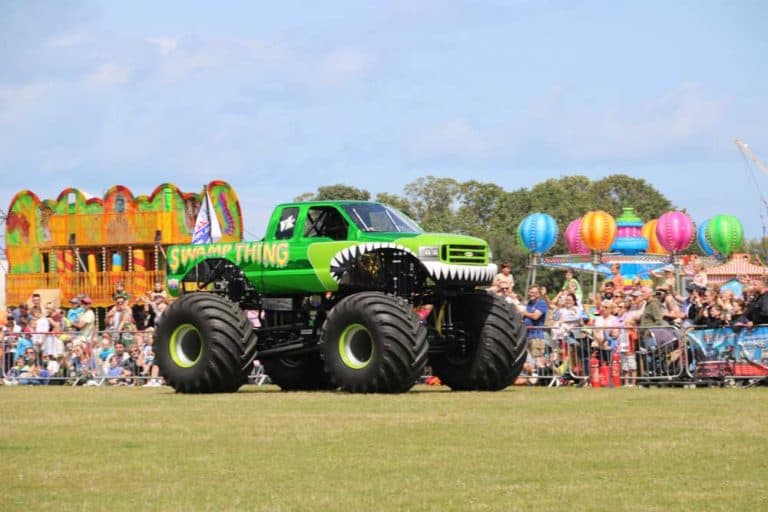 Green monster truck with large tires at a fairground event.